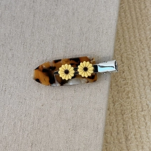 Vue détaillée d'une pince à cheveux en acétate avec motif écaille et marguerites jaunes