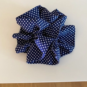 Detail view of navy blue polka dot scrunchie with soft pleated fabric texture