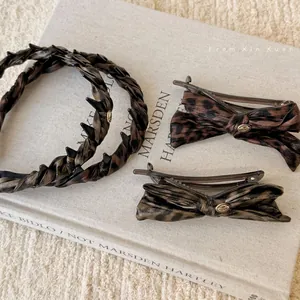 Leopard print bow hair clips and slim headbands with gold love charms on book