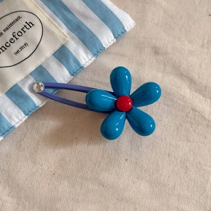 Vue détaillée de la barrette fleur bleue avec pétales en résine et clip bb violet