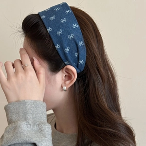Dettaglio del cerchietto in denim blu con fiocchi bianchi indossato da una modella