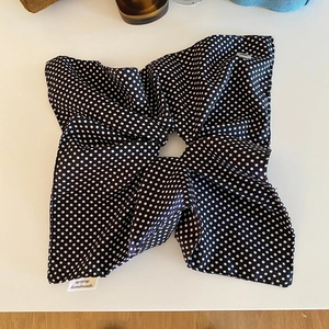 Detail of white handmade woven label on a large black and white polka dot fabric scrunchie
