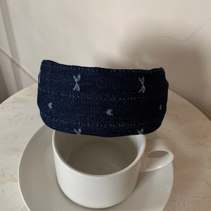 Dettaglio di fascia in denim blu scuro con ricamo di stelle blu su una tazza