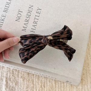 Detail of leopard print bow hair clip with gold heart button featuring love engraving