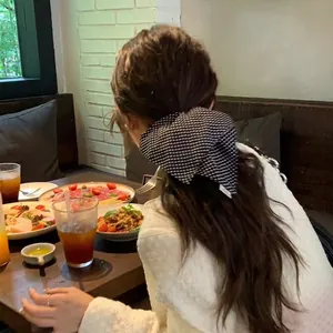 Korean style black and white checkered bow hair scrunchie worn in a cafe setting