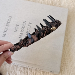 Close-up of leopard print fabric headband with golden Love tag and plastic hair comb