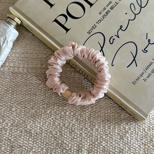 Gros plan détaillé du chouchou en satin rose avec plis doux sur un livre français