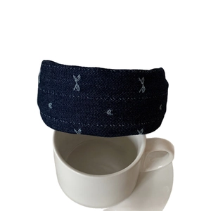 Cerchietto in denim blu scuro con ricami bianchi mostrato da una prospettiva laterale