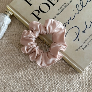 Détail du chouchou en soie rose champagne élégant avec éclat nacré sur le tissu doux
