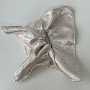 Detailed macro shot of champagne satin hair scrunchie with sparkling rhinestones