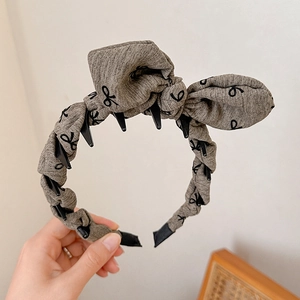 Detail of grey-brown bow headband with black patterns and non-slip inner teeth