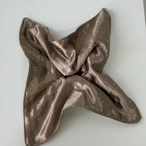 Macro shot of bronze satin silk headscarf featuring sparkling rhinestone embellishments