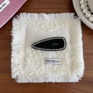 Barrette goutte noire élégante avec strass sur un fond texturé et doux