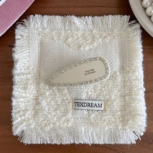 Barrette goutte blanc cassé élégante avec strass colorés sur fond de bois naturel