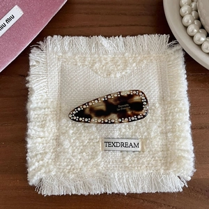 Gros plan sur une barrette en écaille de tortue sertie de strass et lettrage doré