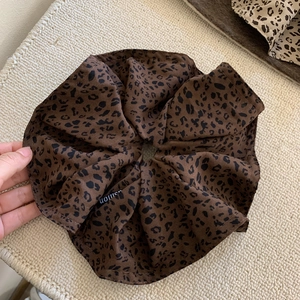 Detailed view of leopard print oversized scrunchie with fashion label on woven mat