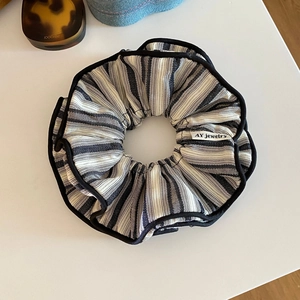 Detail of black and white striped scrunchie with AY jewelry label on woven fabric
