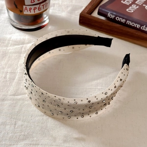 Sparkling rhinestones mesh wide headband with silver studs on a white textured cloth