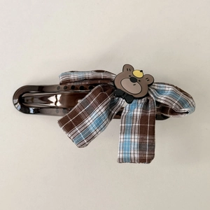 Detail view of a plaid bow hair claw clip with a cute cartoon bear and resin base