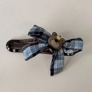 Close-up of brown hair clip with navy plaid bow and cute bear head detail