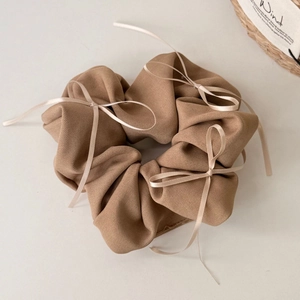 Détail d'un chouchou kaki avec nœuds en satin rose en tissu de coton sergé doux