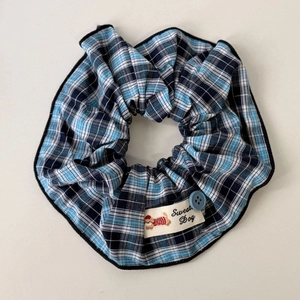 Close-up of blue plaid scrunchie featuring a cute cartoon dog patch and decorative button