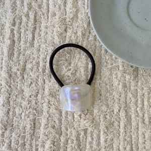 Detail showing the iridescent handmade square charm on a durable elastic hair tie