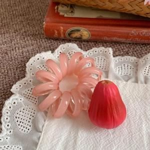 Détail macro d'un élastique à cheveux rose en spirale posé sur de la dentelle blanche