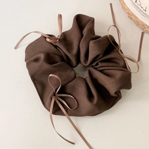Détail d'un chouchou marron café avec texture rayée et petits nœuds décoratifs