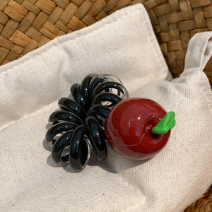 Détail du pendentif pomme rouge sur élastique spirale noir et transparent dans un panier