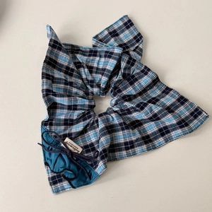 Macro shot of blue and black plaid fabric hair tie with hellocandy brand label detail