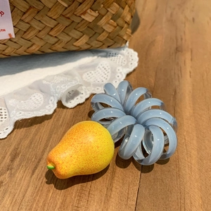 Gros plan d'un élastique spirale bleu orné d'un pendentif en forme de poire jaune