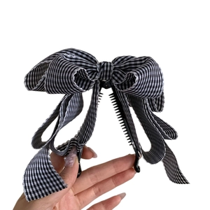 Eleganter Haarklammer mit schwarz-weißer Gingham-Schleife gehalten auf weißem Hintergrund