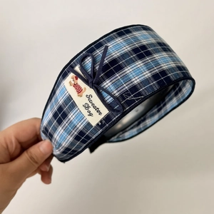 Detail of blue plaid headband with a cute bow and Sweater Dog fabric label