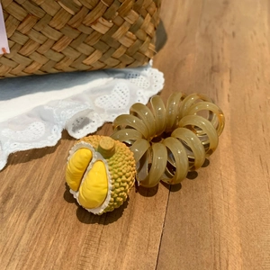 Détail d'un élastique spirale avec un pendentif réaliste en forme de fruit durian