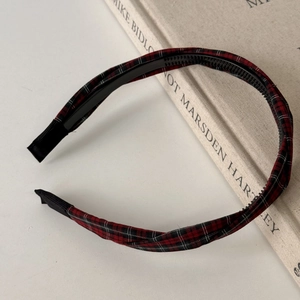 Detail of red and black tartan plaid headband with anti-slip inner teeth over beige book