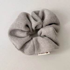 Macro shot of gray plush velvet scrunchie showing soft texture and detailed white side label