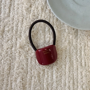 Detail view of burgundy resin hair tie featuring gold France Handmade lettering