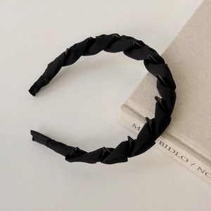 Detail of black twisted fabric headband with anti-slip teeth on a minimalist background