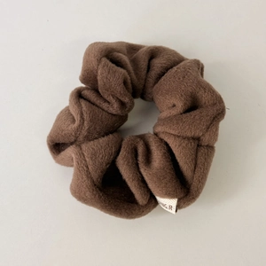 Close-up of soft plush coffee brown scrunchie with detailed fabric texture and logo tag