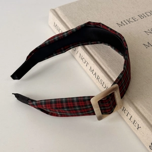 Macro shot of a red plaid headband with a square buckle on a vintage book