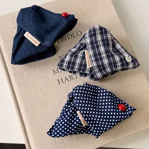 Three handmade fabric hair claws in denim, plaid, and polka dots on a linen book