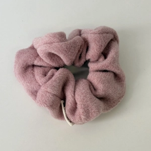 Close-up of soft pink plush scrunchie showing thick faux lamb wool texture and elastic core