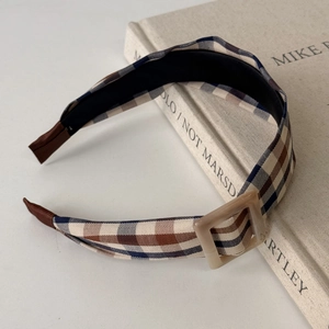 Close-up of retro plaid headband with square buckle detail on a book background