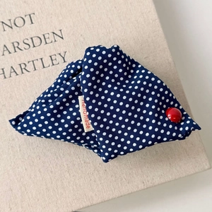 Detail of blue polka dot fabric hair claw clip with handmade tag and red button
