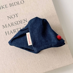 Close-up of denim fabric hair clip with red bead and a Handmade woven label detail