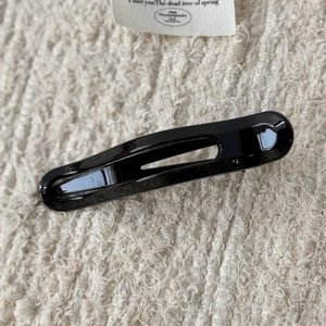 Détail d'une pince à cheveux en résine noire brillante avec un design ovale évidé épuré