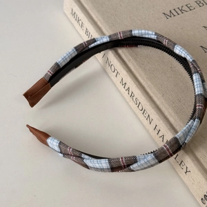 Detail view of plaid headband with non-slip teeth and comfortable ribbon edges