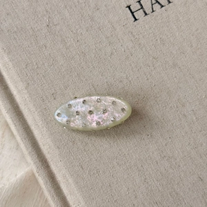 Barrette ovale en acétate avec strass et fini nacré blanc aux reflets irisés doux
