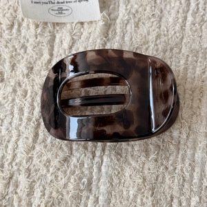 Détail d'une pince à cheveux motif léopard sur une surface en tricot beige doux
